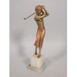 An Art Deco cold painted bronze figure of a female golfer, on a stepped onyx base, unmarked, 26cm