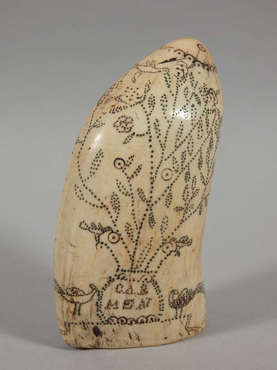 A 19thC scrimshaw, with punched decoration in the form of a tree, birds, and a flag bearing the