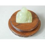 A 20thC green oriental hardstone figure of Pudai, on a hardwood base, 10cm diameter.