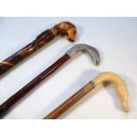 Three various folk art walking sticks, to include one with white metal salmon head, on rustic turned