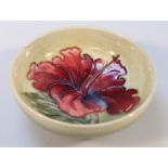 A Moorcroft Hibiscus pattern dish, the circular body with a green ground on circular foot, impressed
