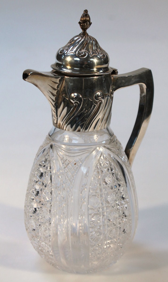 A Victorian silver and cut glass claret jug, with a floral domed lid headed by an acorn finial