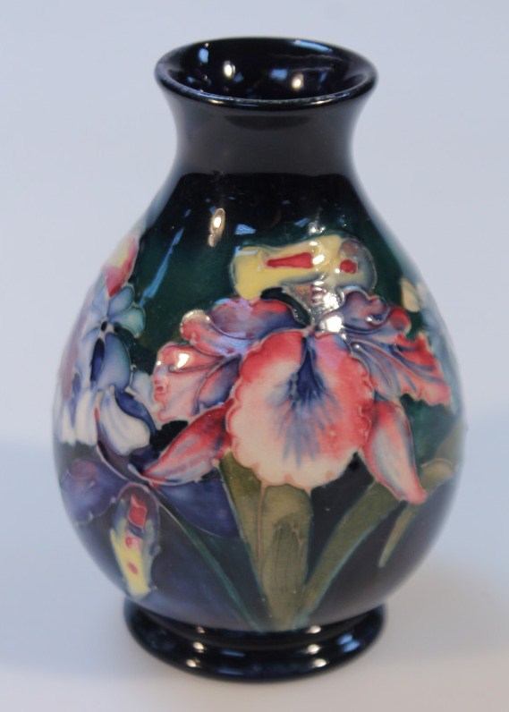 A 20thC Moorcroft Orchid pattern vase, the circular bellied body with a blue ground on circular