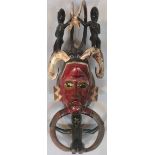 An Ivory Coast Baoule wooden tribal mask, with carved figures the central face painted red with gold