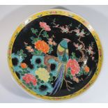 A 19thC Japanese famille noir charger, the circular body hand painted with an exotic bird on a