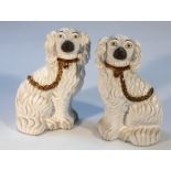 A pair of early 20thC Staffordshire pottery spaniels, each press moulded with gilt collars and