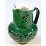 A late 19thC/early 20thC earthenware jug, the bellied body green glazed and sgrafitto decorated with