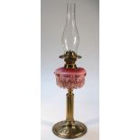 A late Victorian brass Art Nouveau design oil lamp, the clear glass funnel raised above a part