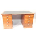 A 1930s oak twin pedestal desk, having brass demi lune handles upon four short drawers on each