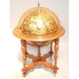 A mahogany drinks globe, upon quadripartite base, with turned column supports on brass castors,