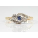 A diamond and sapphire crossover ring, with central sapphire stone flanked by two illusion set