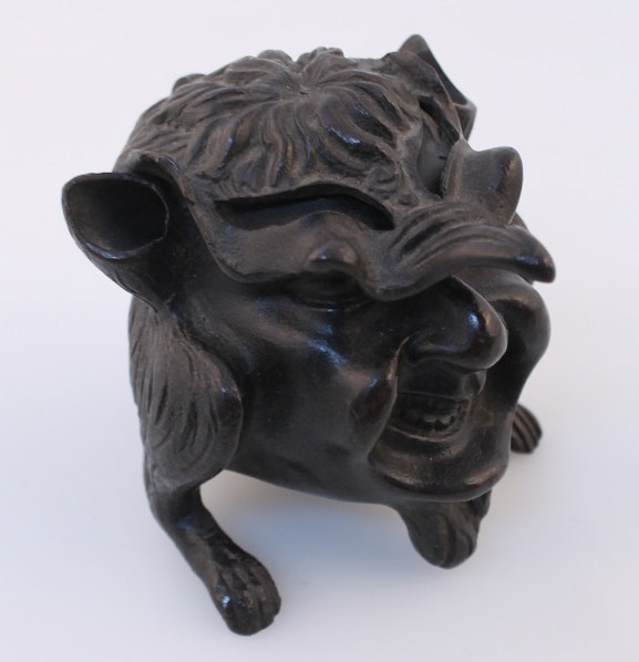 A late 19th/early 20thC bronze inkwell, in the form of a smiling satyr with hinged lid on triple