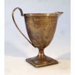 A George III silver cream jug, the helmet shaped body with beak spout and strap handle on inverted