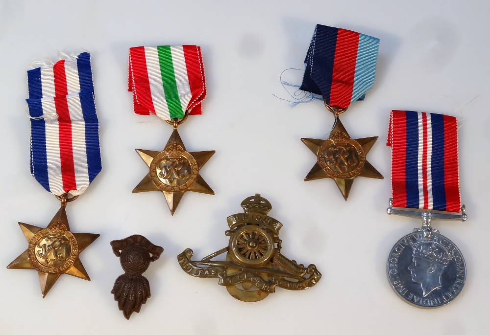 Various WWII medals, comprising three Stars, Campaign and two cap badges, in a box addressed to