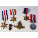 Various WWII medals, comprising three Stars, Campaign and two cap badges, in a box addressed to