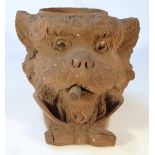 An early 20thC black forest tobacco jar, in the form of a smoking dog, with glass eyes wearing bow