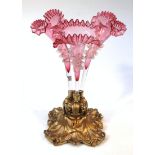 An early 20thC cranberry and clear glass three branch epergne, set with three compressed trumpet