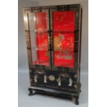 A 20thC Chinese lacquer finish display cabinet, the rectangular outline fronted by two doors hinging