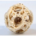 A later Meiji period Japanese ivory puzzle ball, of shaped circular form, carved with an outer