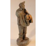 An unusual terracotta figure, of a gentleman in flowing robes holding a basket to his front, on a
