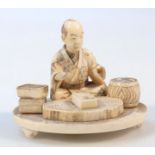 A Japanese Meiji period ivory figure group, of a scholar in flowing robes with legs crossed before