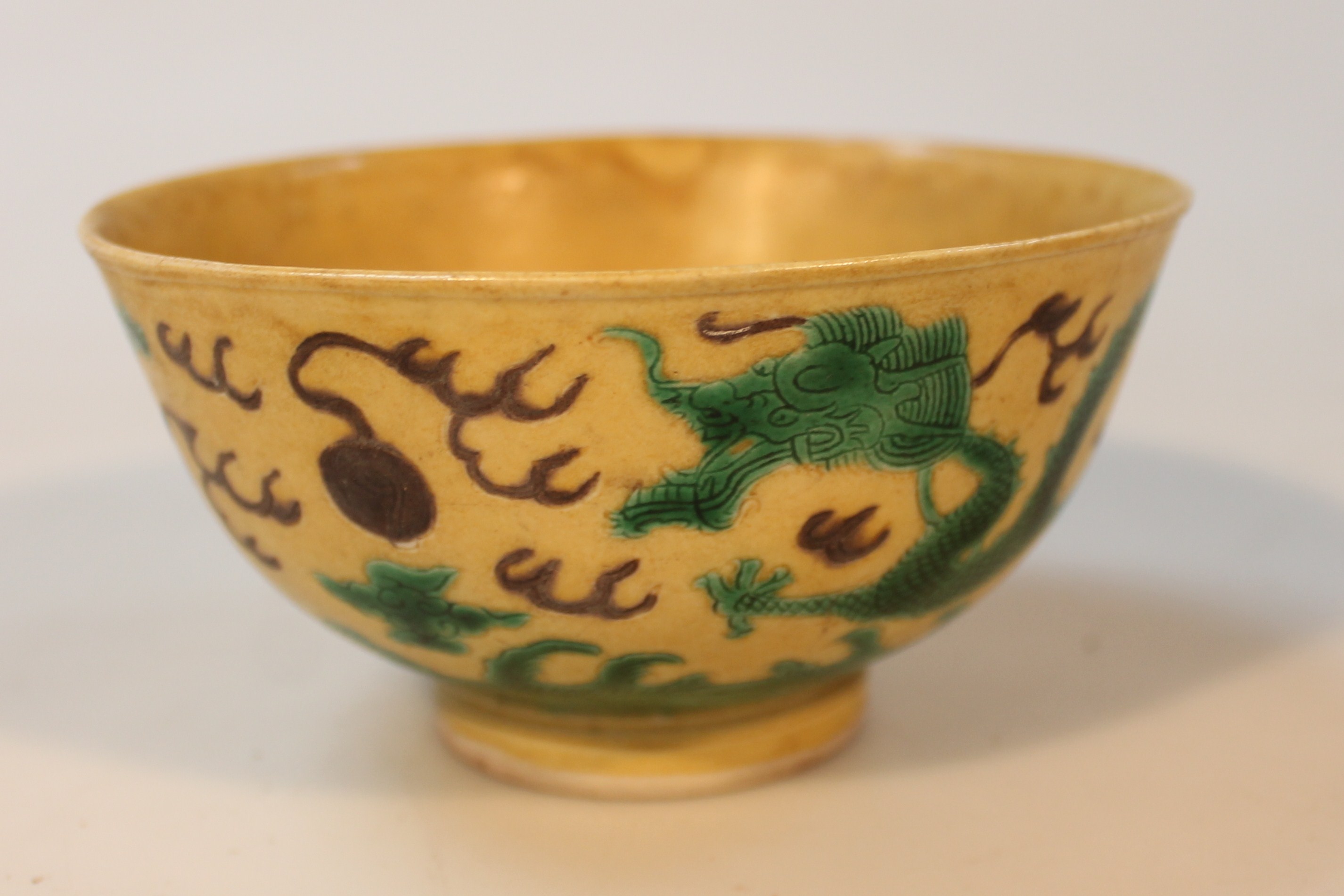 A Chinese porcelain yellow and green ground bowl, decorated with dragons and foliage on a circular