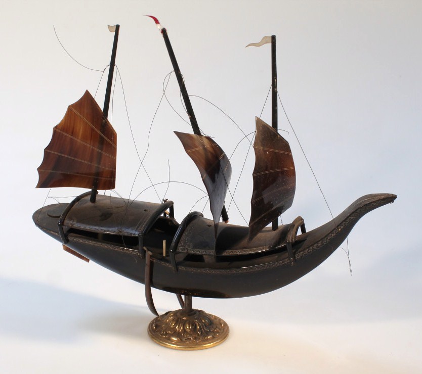 An early 20thC carved horn ship, with shaped masts and realistic decking on a cylindrical stem