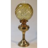 A 20thC brass oil lamp, with amber glass shade and clear funnel on a turned fluted stem and circular