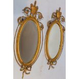 A pair of 19thC giltwood and Gesso wall mirrors, each headed by urns and flanked by scrolls, the