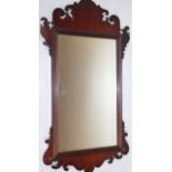 An early 20thC Chippendale mahogany framed wall mirror, with a heavily carved outline and a plain