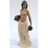 A Lladro figure, no. 2323 formed as a lady water carrier semi-clad, predominately glazed in grey and