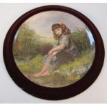 A late 19thC earthenware wall plaque, decorated with a child seated collecting sticks, in colours,