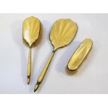 A yellow enamel three piece dressing table set, comprising hand mirror, 36cm high, clothes brush and