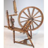 An early 20thC elm spinning wheel, set with various turned articulated sections and a spoked wheel