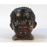 An early 20thC tobacco jar and cover, formed as a black boys head with removable top, he smiling and