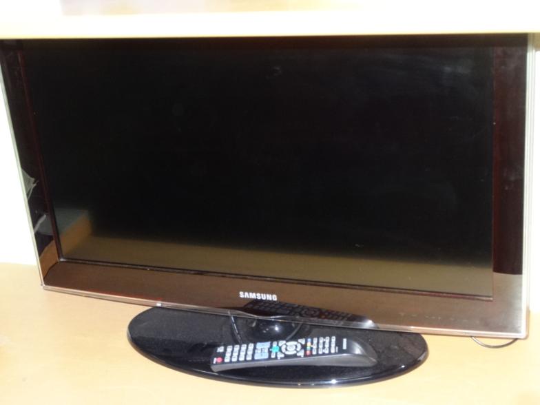 A Samsung 32" flat screen television, in black on an oval plinth stand with accessories.