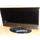 A Samsung 32" flat screen television, in black on an oval plinth stand with accessories.