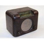 A mid-20thC bakelite cased radio, with a shaped outline and a material meshwork speaker front,