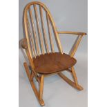 A 20thC Ercol style lightwood rocking chair, with an arched stick back, shaped arms and seat on a