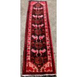 An Iranian Baluch rug, in red and cream with a bird motif, 292cm x 72cm.