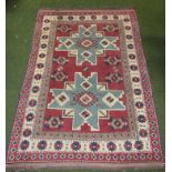 An early 20thC rectangular Middle Eastern hearth rug, with a geometric cross centre in blue, pink