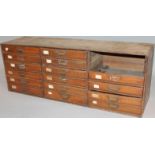 A late 19thC oak bank of drawers, set with three columns of six drawers, each with metal swan neck