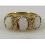 A ladies three stone opal ring, on yellow metal shank marked 18, size 0.