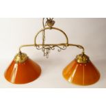 A gilt metal twin pendant light fitting, with amber glass shades.