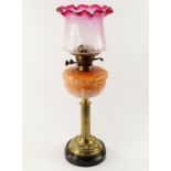 A Victorian brass oil lamp, with duplex burner, reeded column and supporting a glass reservoir