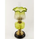 A Victorian brass oil lamp, with duplex burner and green clear glass reservoir and green graduated