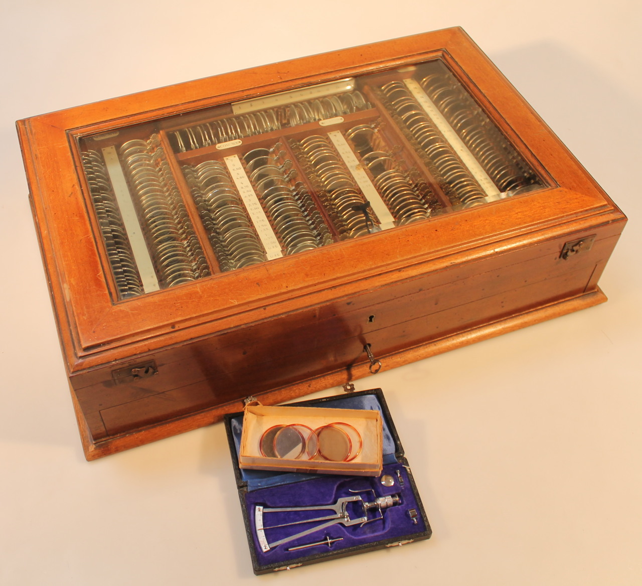 An early 20thC mahogany opticians tester lens set, the rectangular box with a bevelled glass door,