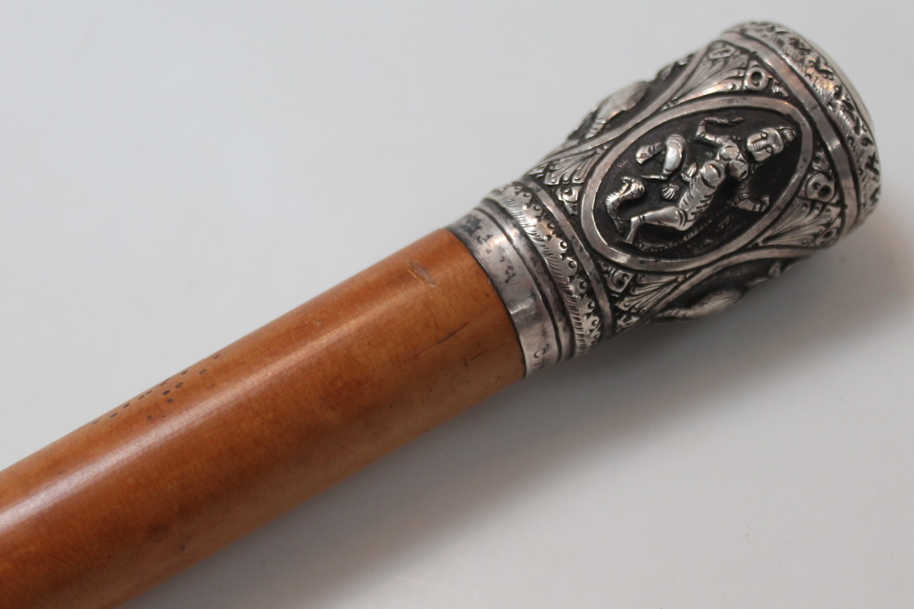 An early 20thC lightwood cane, the cylindrical stem headed by a knop raised with elephants and