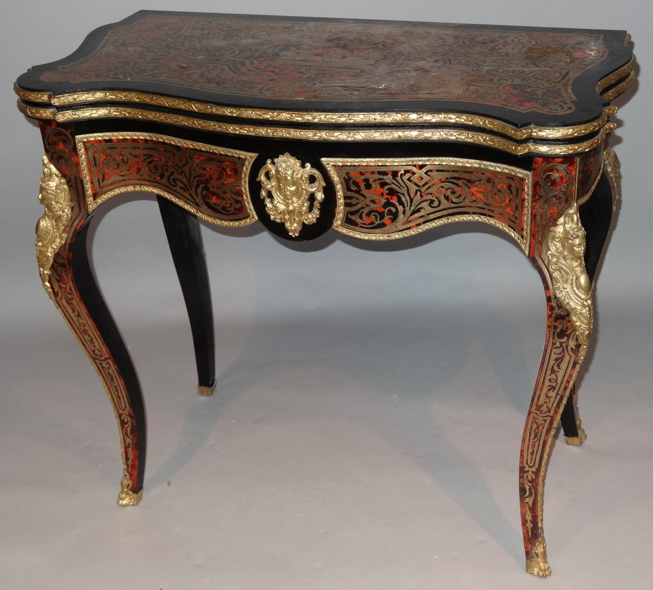 A 19thC French Boulle ebonised and ormolu games table, with serpentine outline the top fronted by