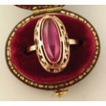 A 20thC Russian dress ring, set with an oval red stone in a pierced setting, yellow metal marked